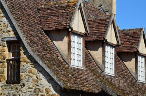 Charming rustic stone facade with traditional roof and windows in natural sunlight.