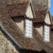 Charming rustic stone facade with traditional roof and windows in natural sunlight.