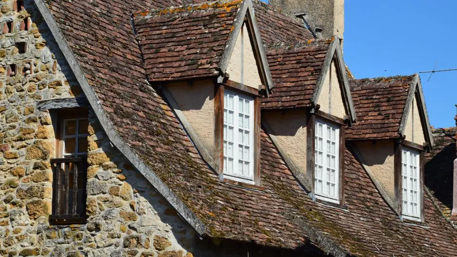 Charming rustic stone facade with traditional roof and windows in natural sunlight.