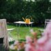 Yellow watering can on a small table in a garden.
