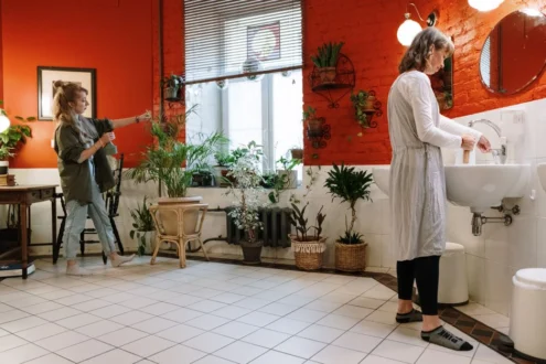 Two women tending to lush indoor plants in a cozy room, showcasing modern home gardening.