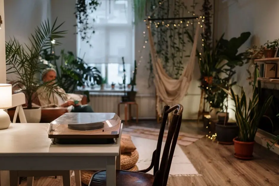 A cozy living room with plants, a hammock, and a vintage turntable, perfect for relaxation.